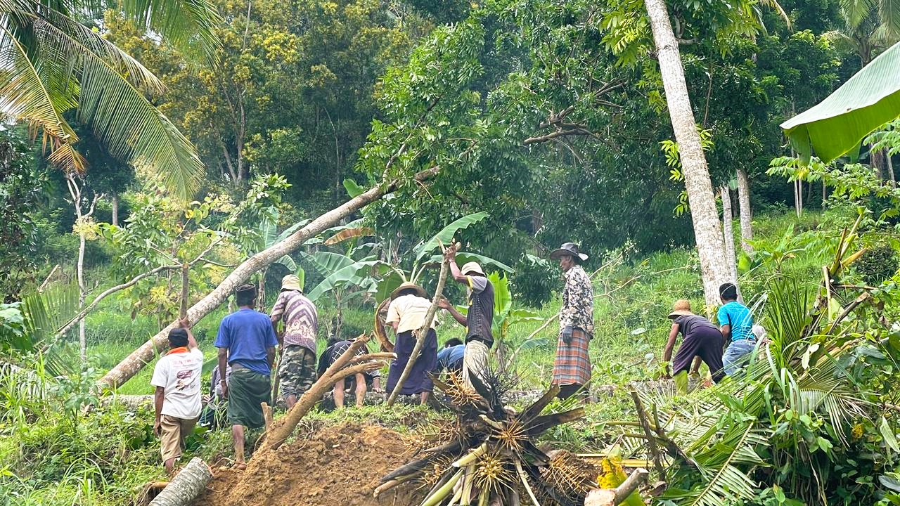 TERISOLASI: Warga Dusun Laok Gunung, Desa Sana Daja, Kecamatan Pasean, sedang membersihkan tanah longsor yang menutup akses jalan, Selasa (27/1).