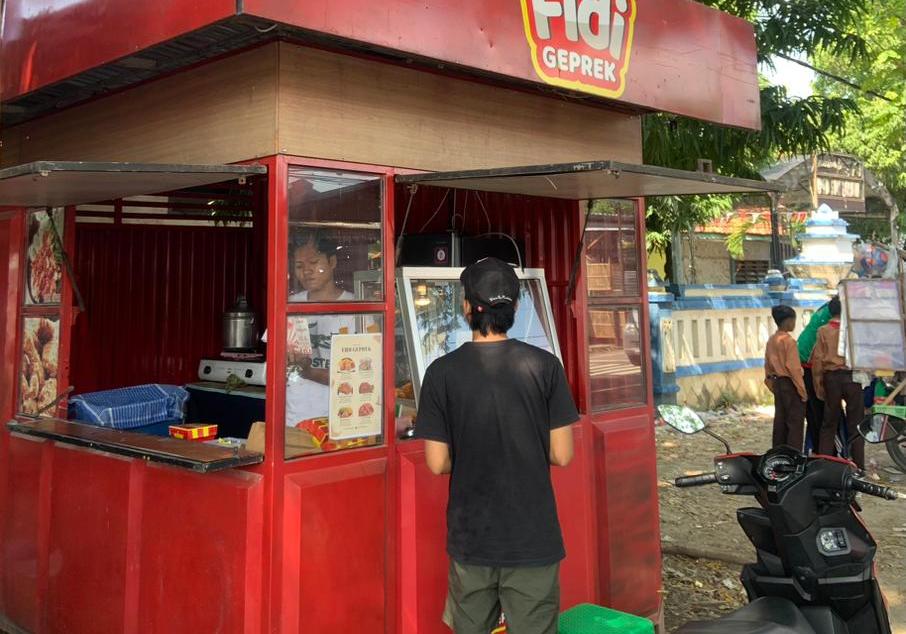 SANTAI: Seorang pemuda sedang memilih menu Fidi Geprek Jalan Raya Torjun, Sampang.