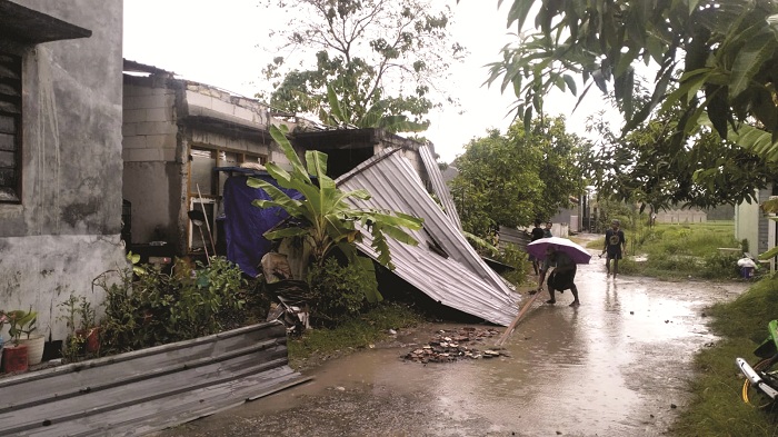 MUSIBAH: Warga membersihkan sisa puing-puing rumah yang rusak akibat angin kencang di Desa Taddan, Kecamatan Camplong, Sampang, Minggu (1/2). (BPBD UNTUK JPRM)