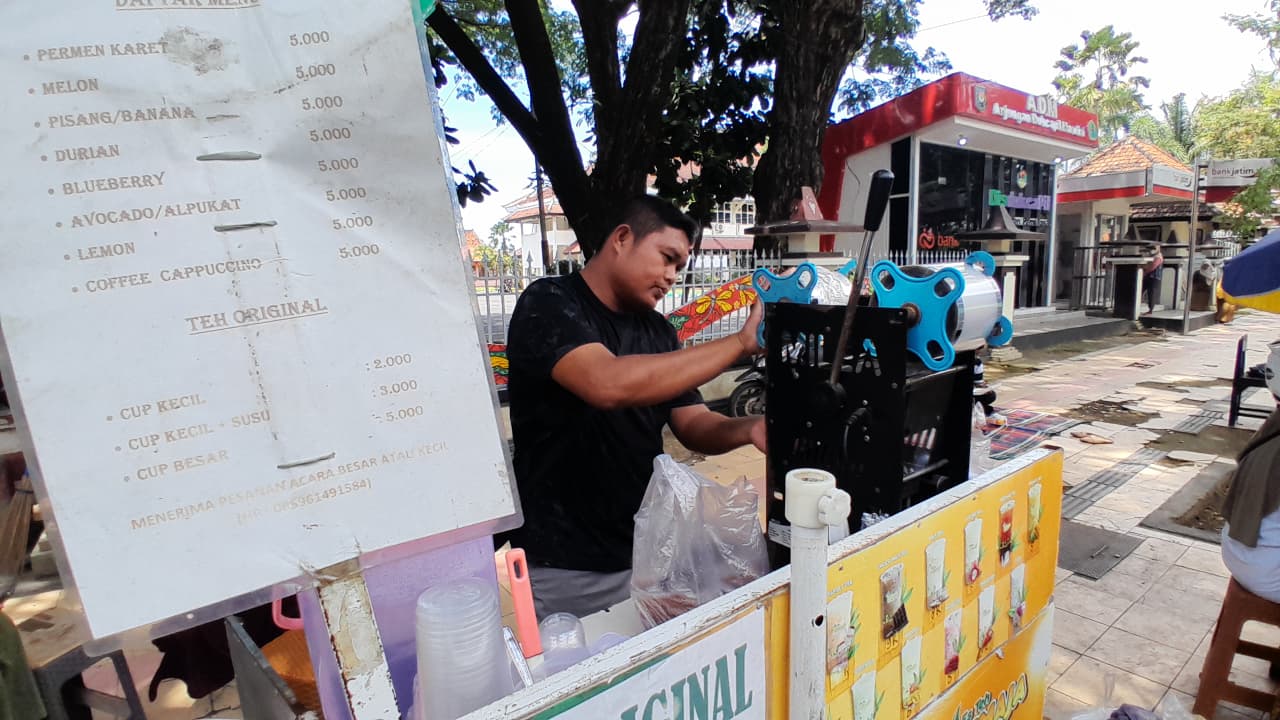 SUMBER PENDAPATAN: Pelaku usaha minuman sedang berjualan di Jalan Kabupaten, Kelurahan Bugih, Pamekasan, Senin (2/2).