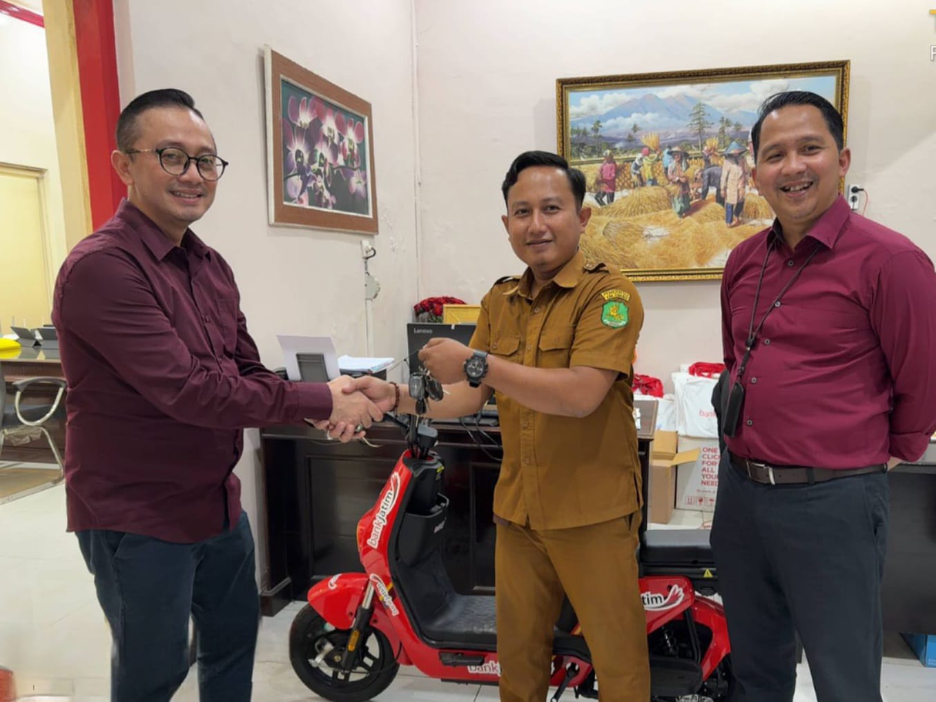 SALING MENGUNTUNGKAN: Pemimpin Cabang Bank Jatim Sumenep Bambang Eko Budi Prakoso menyerahkan kontak sepeda listrik kapada PNS pemenang undian di kantor cabang setempat.