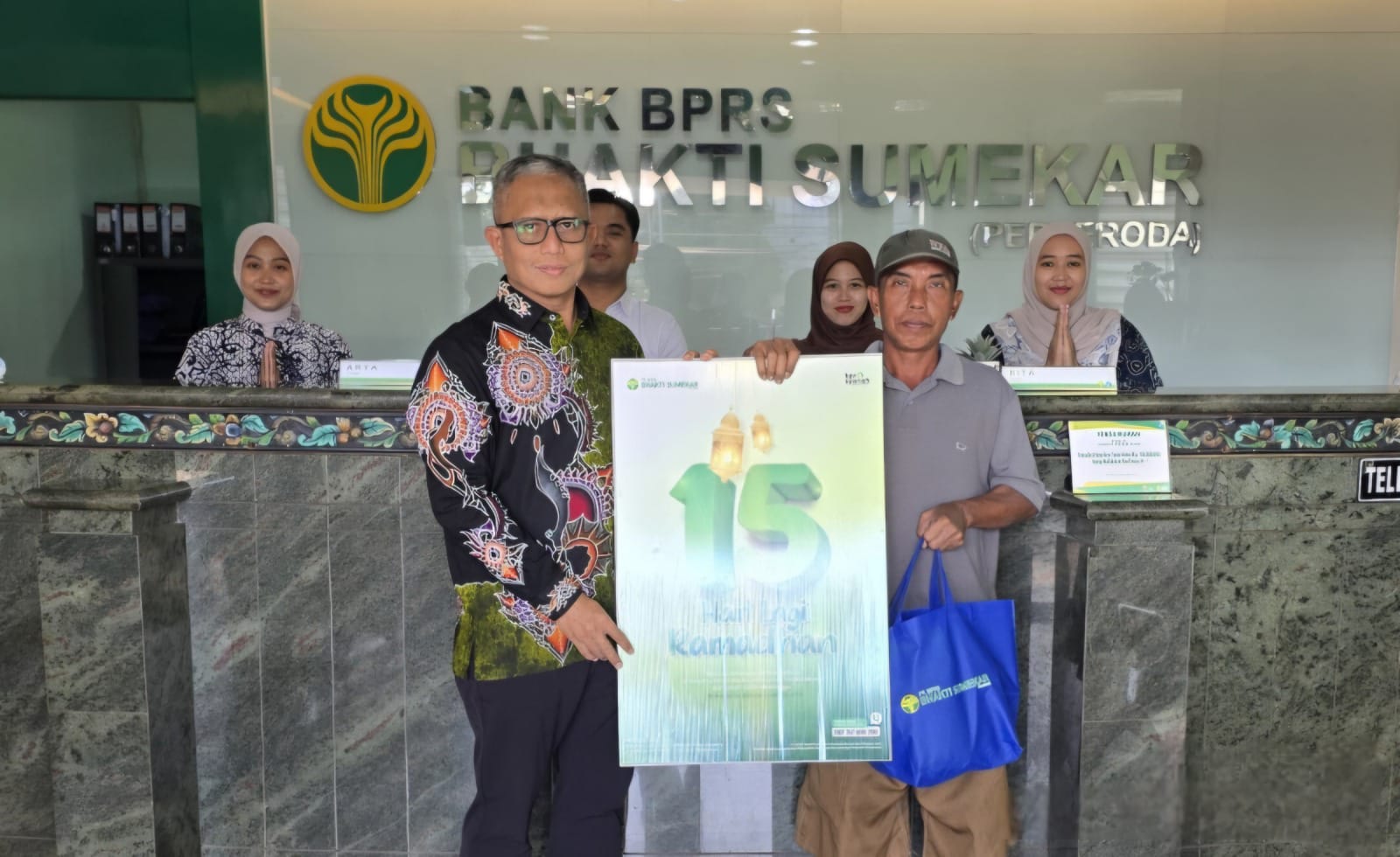 BERBAGI: Direktur Utama BPRS Bhakti Sumekar Hairil Fajar memberikan hadiah pada pengunjung pertama di kantor pusat BPRS Bhakti Sumekar, Selasa (3/2).