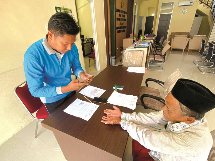 PEMBERKASAN: CJH Mat Sahari menunjukkan paspor di kantor Kemenhaj Sampang Jumat (6/2). (AYU LATIFAH/JPRM)