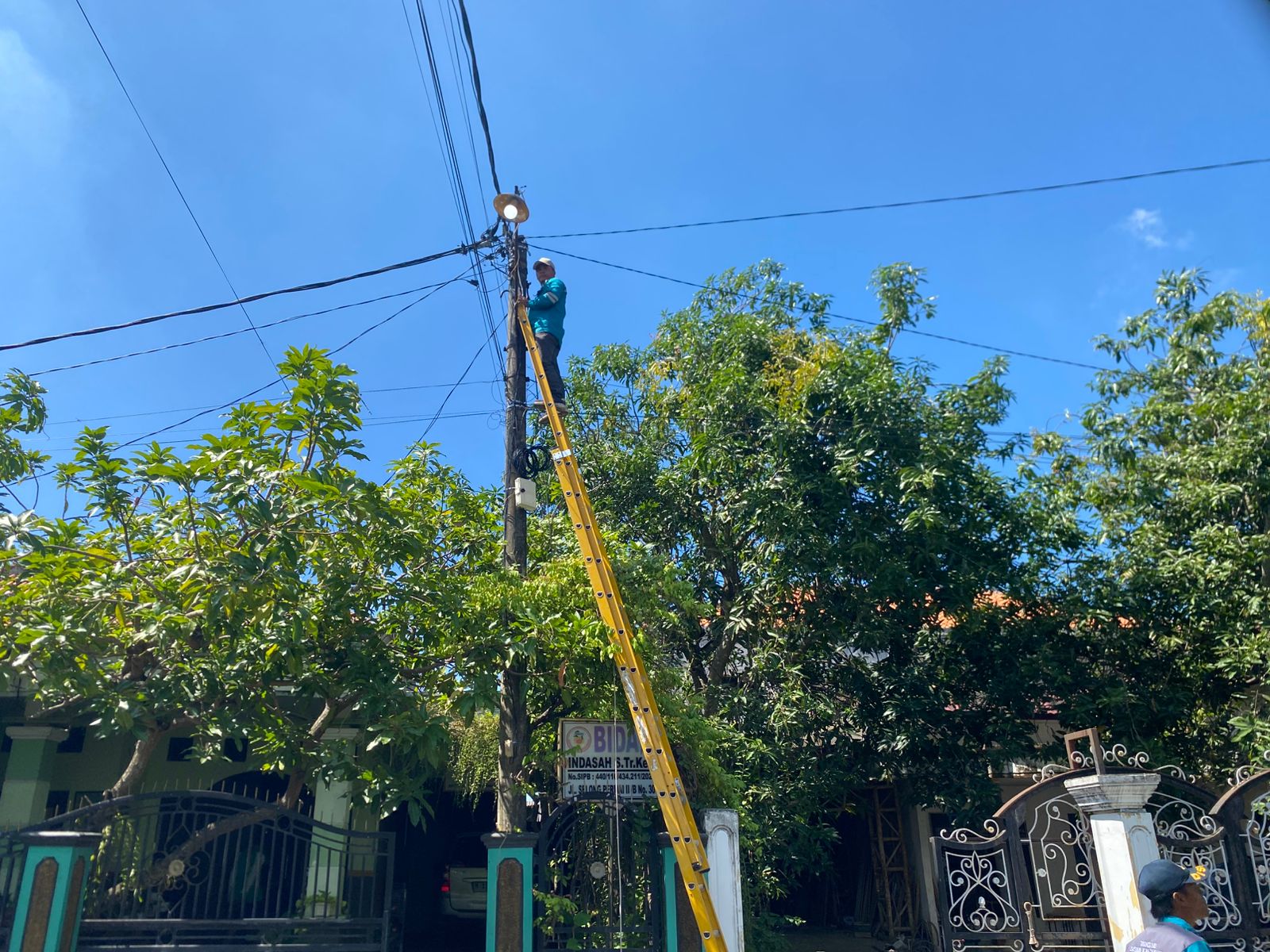 PENERANGAN: Petugas saat memperbaiki lampu dengan tangga beberapa waktu lalu.