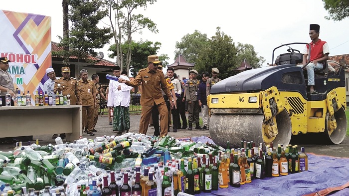 LANGKAH KONKRET: Bupati Pamekasan KH Kholilurrahman secara simbolis memecahkan botol berisi miras dalam pemusnahan barang bukti minuman beralkohol di Pendopo Ronggosukowati Senin (9/2).