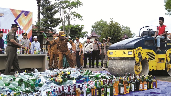 TINDAKAN TEGAS: Wakil Bupati Pamekasan Sukriyanto secara simbolis memecahkan botol berisi miras dalam pemusnahan barang bukti minuman beralkohol di Pendopo Ronggosukowati Senin (9/2).