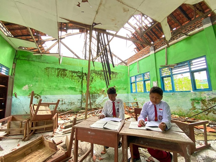 HARAPAN: Hafid Amirullah (kiri) bersama temannya sedang belajar di kelas yang ambruk di SDN Margantoko 1 Desa Margantoko, Jrengik, Sampang, Senin (9/2). (AYU LATIFAH/JPRM)
