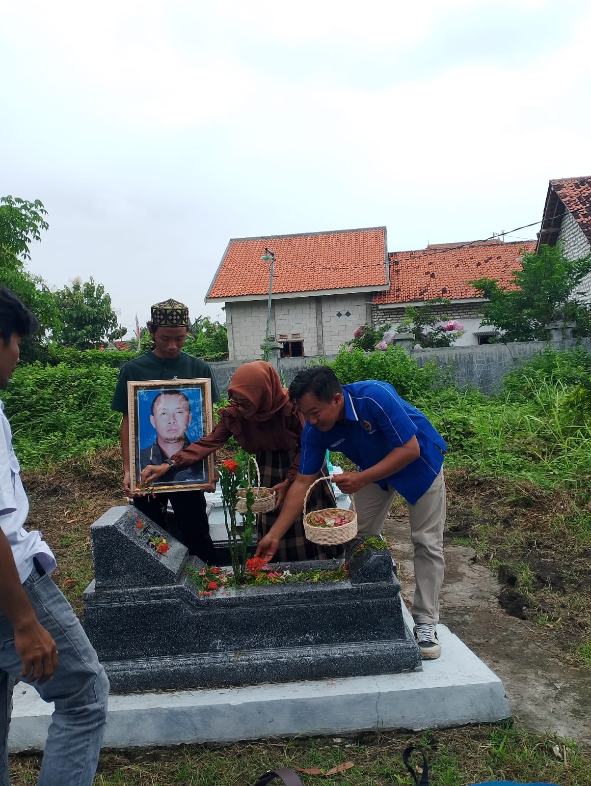 BERDEDIKASI: Ketua PWI Sampang Hanggara Pratama Syahputra (baju biru) menabur bunga di makam pendiri PWI Sampang almarhum Agus Surachman, Senin (9/2).