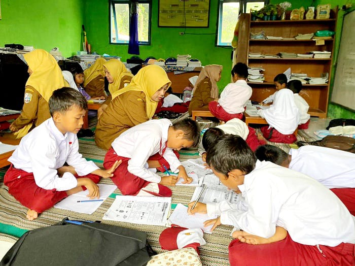 BERBAGI TEMPAT: Siswa kelas I hingga IV saat belajar di ruang guru di SDN Margantoko 1, Kecamatan Jrengik, Sampang, Senin (9/2). (AYU LATIFAH/JPRM)