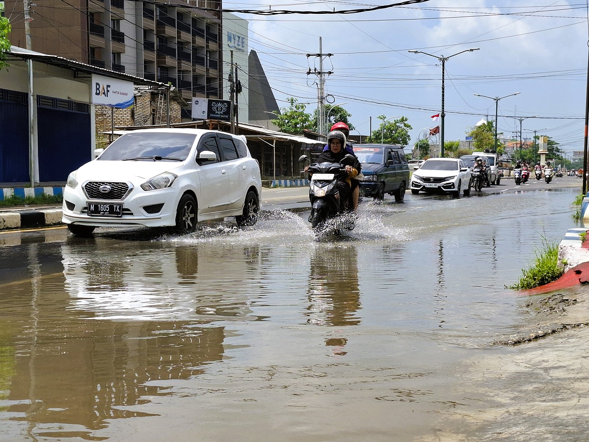 TERGENANG: Pengendara melintas di Jalan Trunojoyo, Gedungan, Batuan, Sumenep, yang tergenang air, Minggu (15/2).
