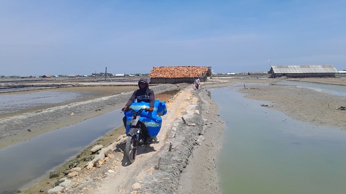 HASIL PRODUKSI: Buruh garam sedang mengangkut garam menggunakan motor di Desa Bunder, Kecamatan Pademawu, Pamekasan, Selasa (23/12/2025). (M. KHOLIL RAMLI/JPRM)