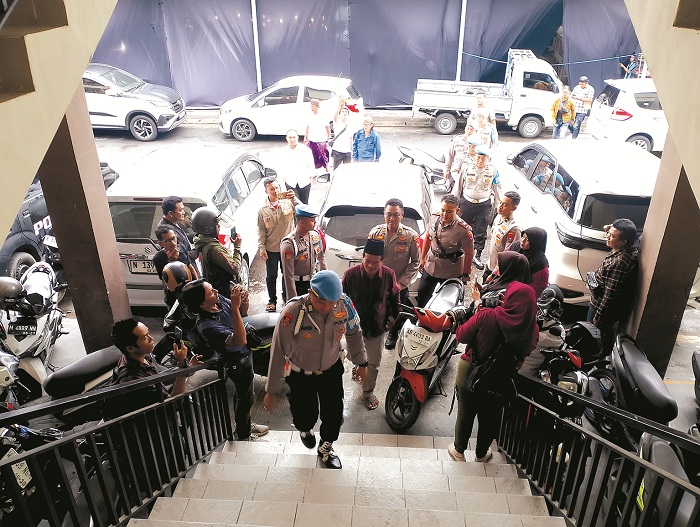 MELANGGAR HUKUM: Terduga pelaku penganiayaan petugas SPBU Mad Jari dikawal polisi saat menyerahkan diri ke Polres Sampang, Rabu (29/10/2025). (UBAIDILLAHIR RAIE/JPRM)