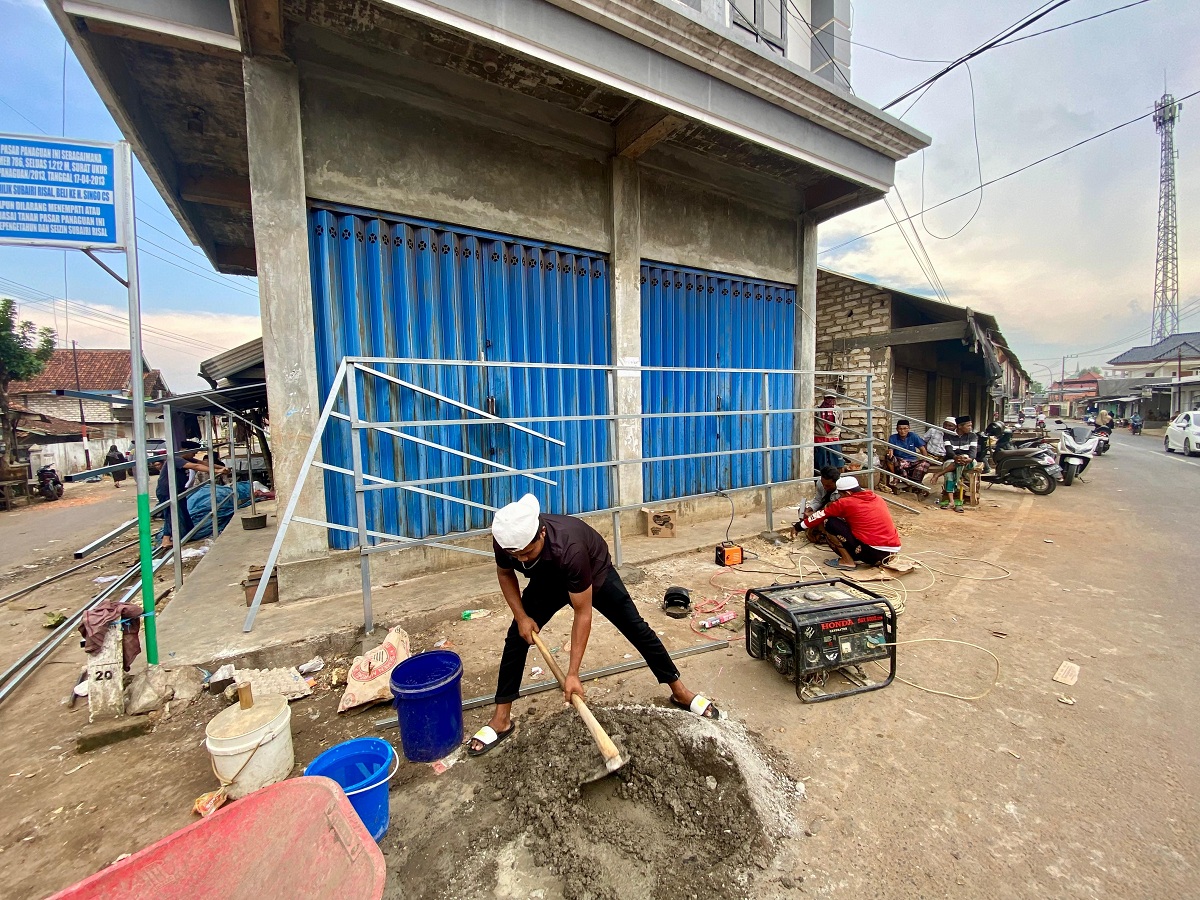 BEKERJA: Pekerja mengaduk semen di toko Pasar Panaguan, Minggu (15/2).