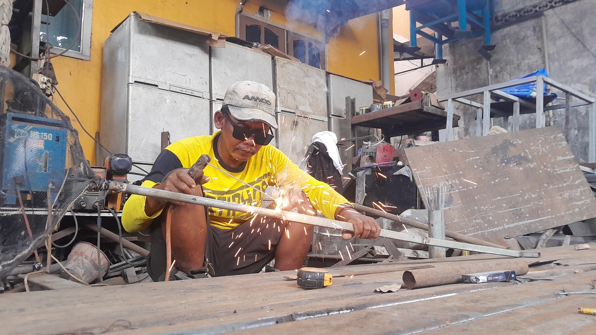 PERLU SKIL: Ahmad, pekerja las di Jalan Amin Jakfar, Kelurahan Gladak Anyar, sedang menyelesaikan pekerjaannya, Rabu (25/2).
