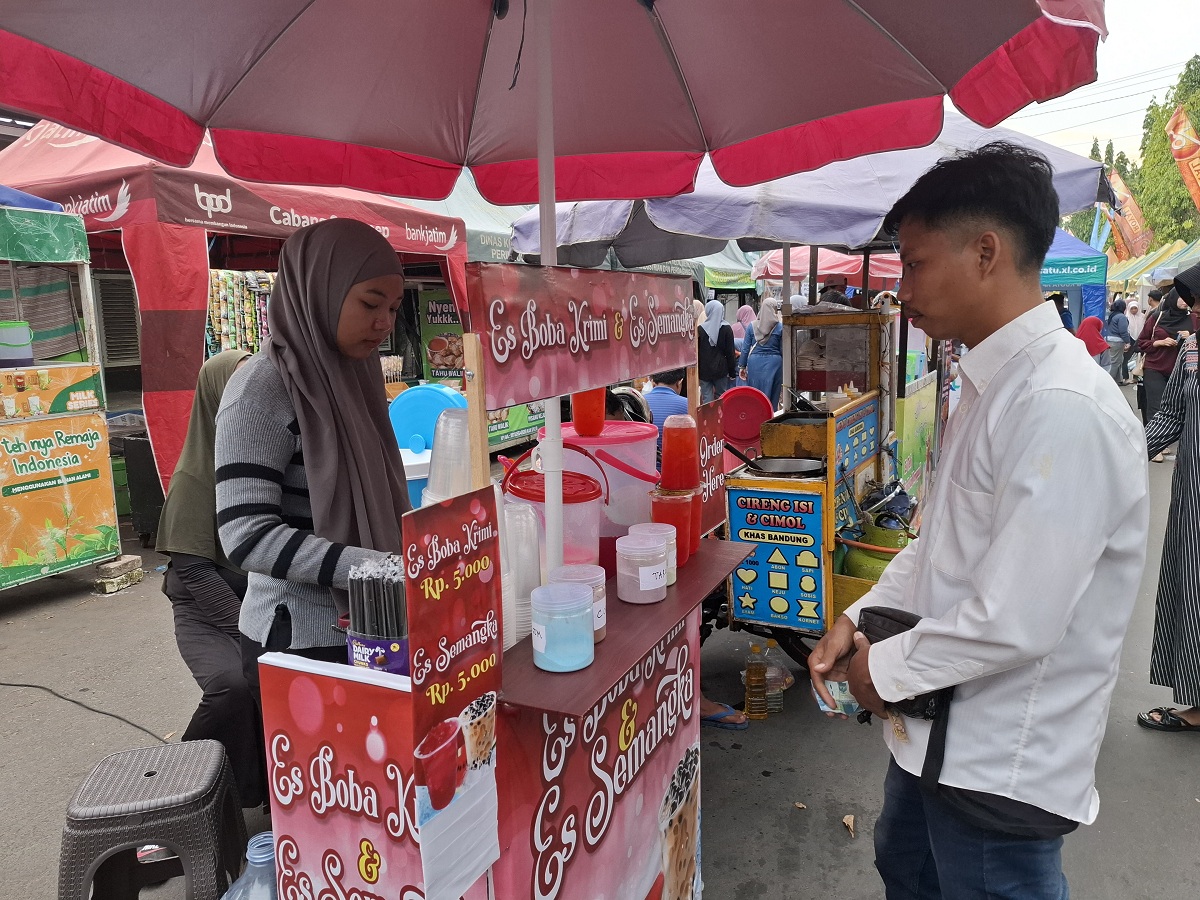 MELAYANI: Fitriani saat melayani pelanggannya di Bazar Takjil Ramadan di Jalan dr Soetomo. Pajagalan, Kecamatan Kota Sumenep, Kamis (26/2).