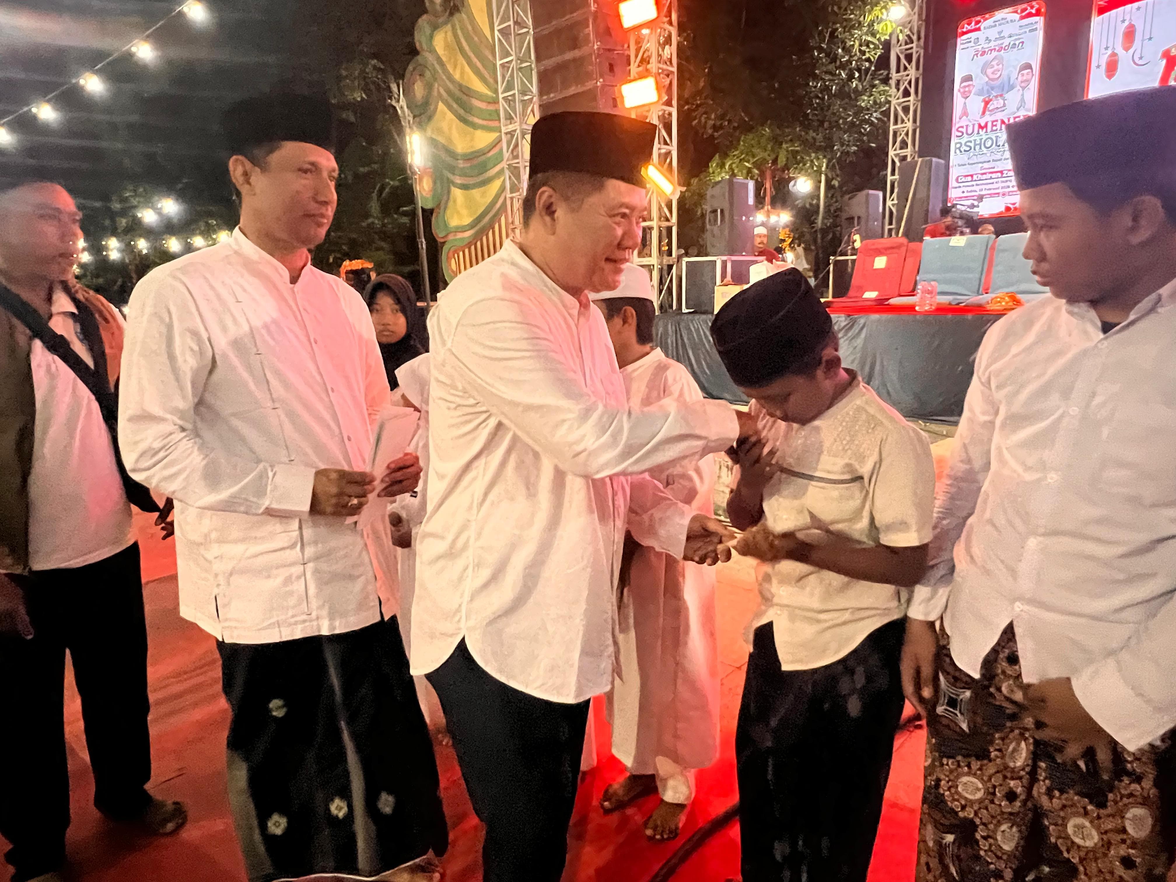 RAMAH: Direktur JPRM Abdul Aziz bersama Sekkab Sumenep Agus Dwi Saputra menyerahkan santunan kepada anak yatim dalam acara Sumenep Bersholawat di sisi timur Taman Pottre Koneng Sumenep, Sabtu (28/2).