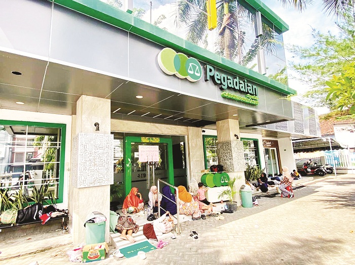 BERTAHAN: Warga berada di Kantor Pegadaian Syariah Pamekasan Minggu (8/3). (MOH. IQBAL AFGANI/JPRM)