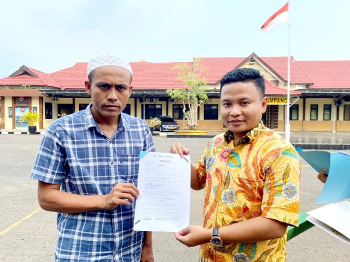 SAH: Muhammad Taufik (batik kuning) kuasa hukum BU (kopiah putih) menunjukkan surat laporan saat ditemui di halaman Mapolres Sampang Senin (9/3). (AYU LATIFAH/JPRM)