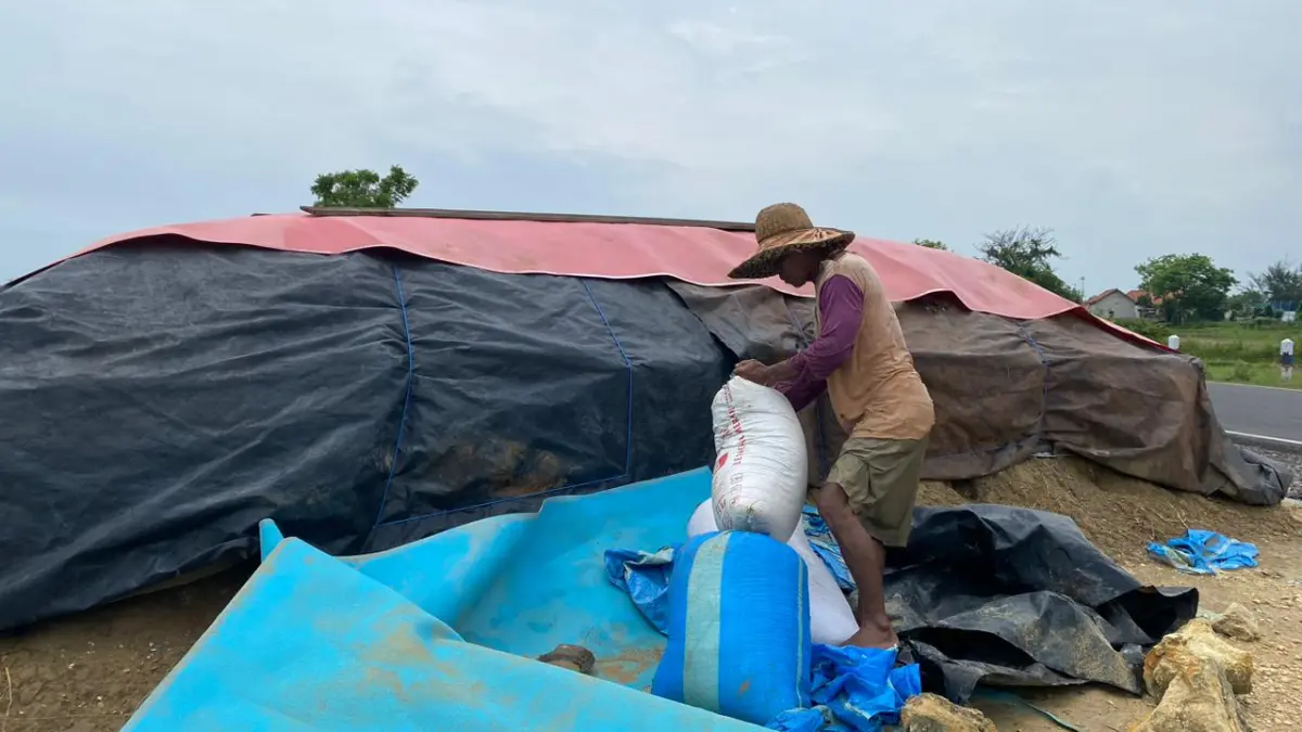 PRODUKSI: Seorang petambak garam saat sedang mengemas garam di Desa Polagan, Kecamatan Sampang, beberapa waktu lalu.
