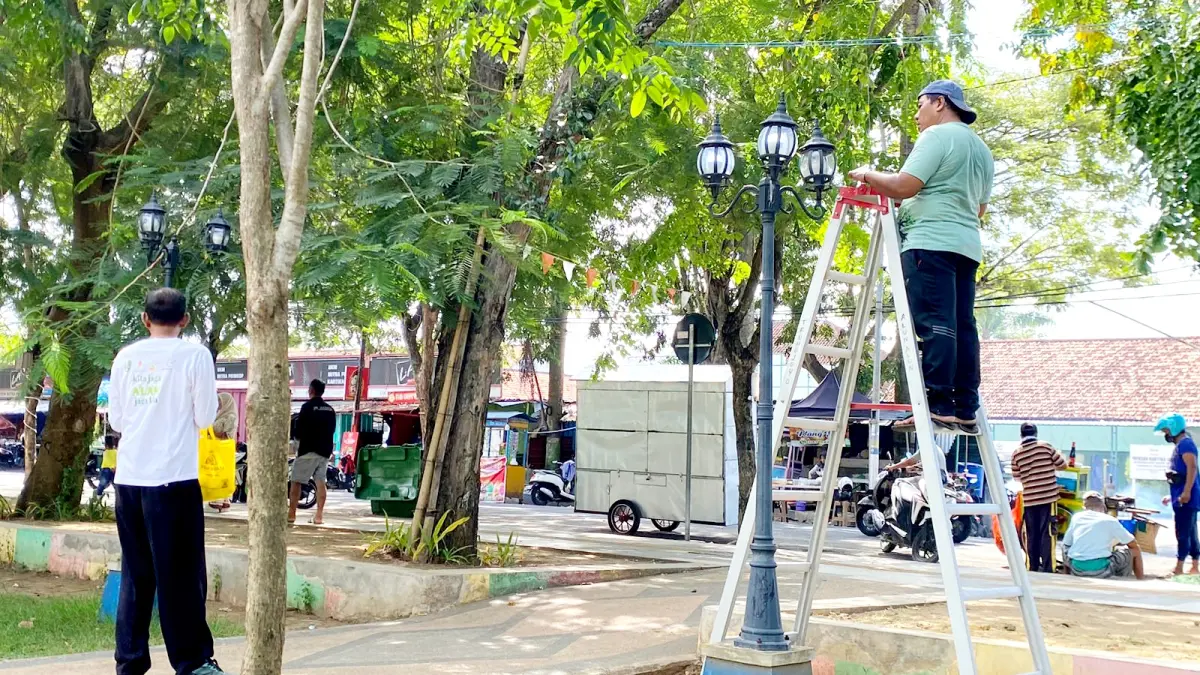 PEMELIHARAAN: Petugas saat memperbaiki lampu hias yang ada di area taman Alun-Alun Trunojoyo, Sampang, Rabu (25/3). (AYU LATIFAH/JPRM)