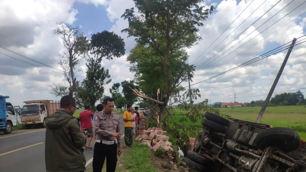 TERGULING: Anggota Satlantas Polres Sampang dan Polsek Jrengik mengecek kendaraan truk yang terlibat laka tunggal di Jalan Raya Desa, Kecamatan Jrengik, Sampang, Selasa (7/4).