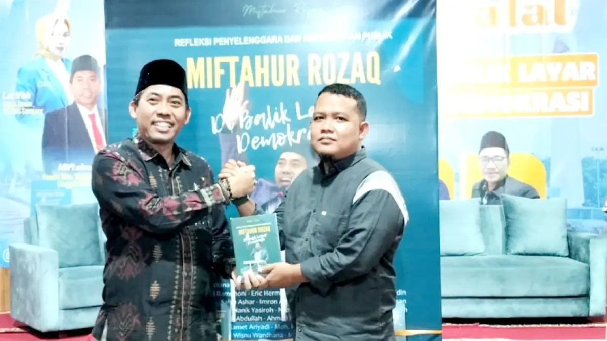 APRESIASI: Komisioner KPU Jatim Miftahur Rozaq menyerahkan buku Di Balik Layar Demokrasi kepada Pemred JPRM Moh. Subhan usai launching di Ruangan Betang Ponpes Assirojiyyah, Kajuk, Sampang, Sabtu (11/4). (ANIS BILLAH/JPRM)