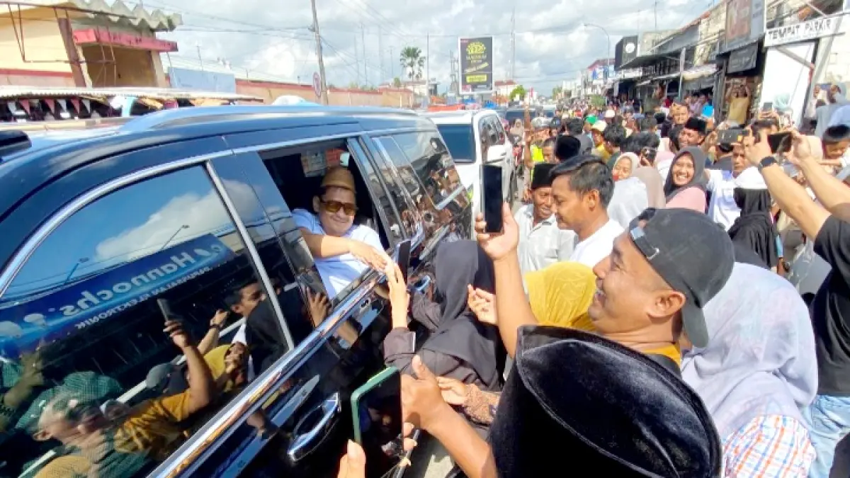 DISAMBUT: Warga bersalaman dengan Haji Her saat melintas di Jalan Raya Blega Minggu (12/4). (JUPRI/JRPM)