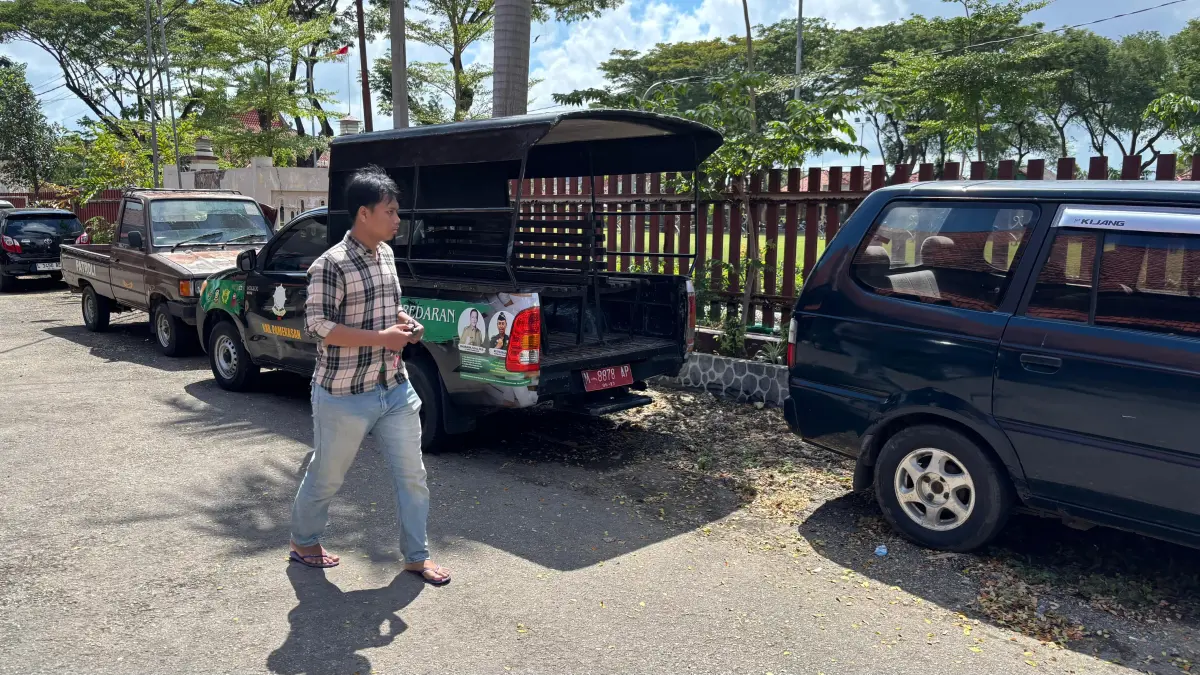 KEBUTUHAN OPERASIONAL: Warga melintas di dekat mobil Satpol PP dan Damkar Pamekasan, Selasa (14/4).