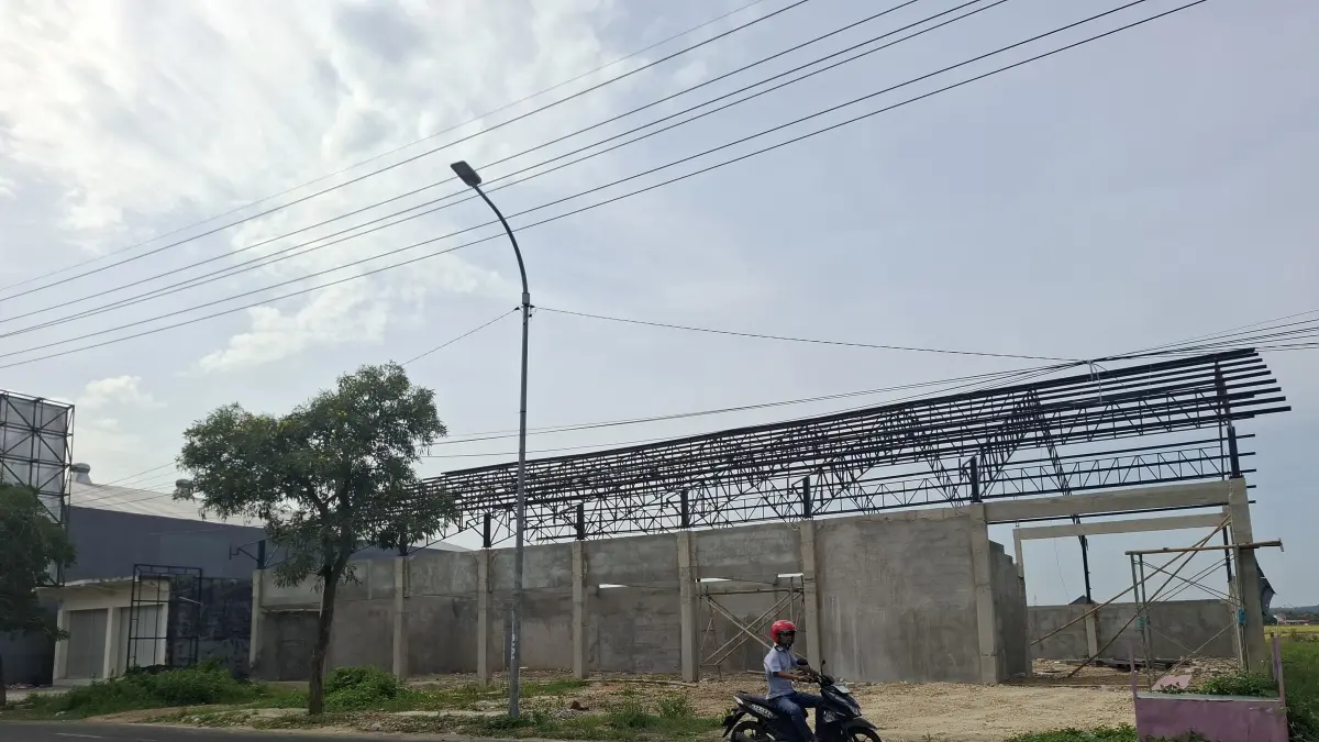 BELUM TUNTAS: Warga melintas di depan gerai KDMP di Jalan Jokotole, Desa Gedungan, Kecamatan Batuan, Sumenep, Selasa (7/4).