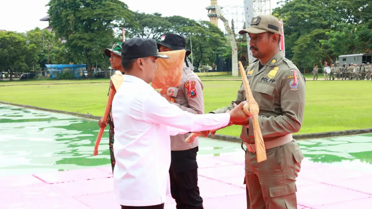 SELAMAT BERTUGAS: Bupati Bangkalan Lukman Hakim menyerahkan peralatan tukang kepada personel program TMMD saat acara pembukaan di alun-alun, Rabu (22/4). (PROKOPIM UNTUK JPRM)