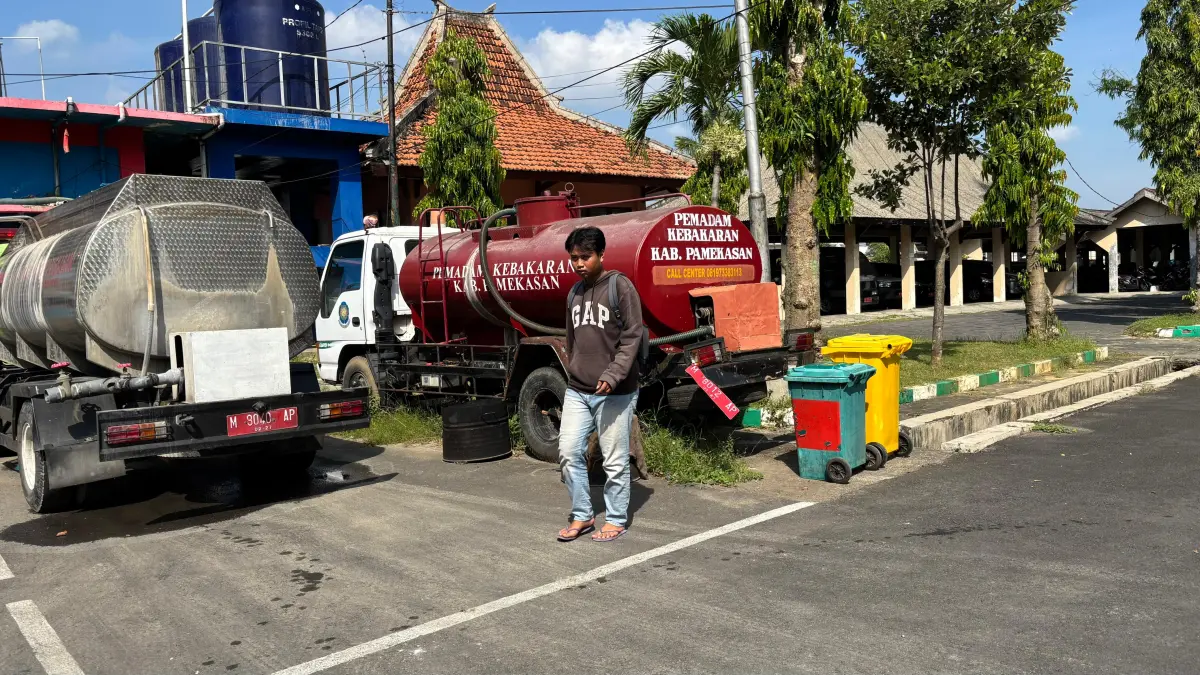 TERIK: Warga berada di sekitar armada pemadam kebakaran, Jumat (24/4).