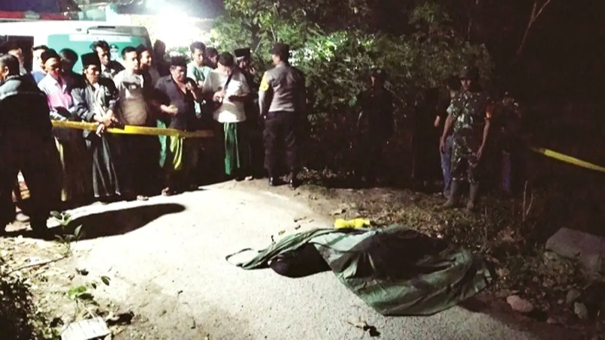 SITA PERHATIAN: Warga berkerumun melihat jenazah ABF yang tergeletak di jalan Desa Lombang Daya, Kecamatan Blega, Bangkalan, Rabu (22/4) malam. (ANIS BILLAH/JPRM)
