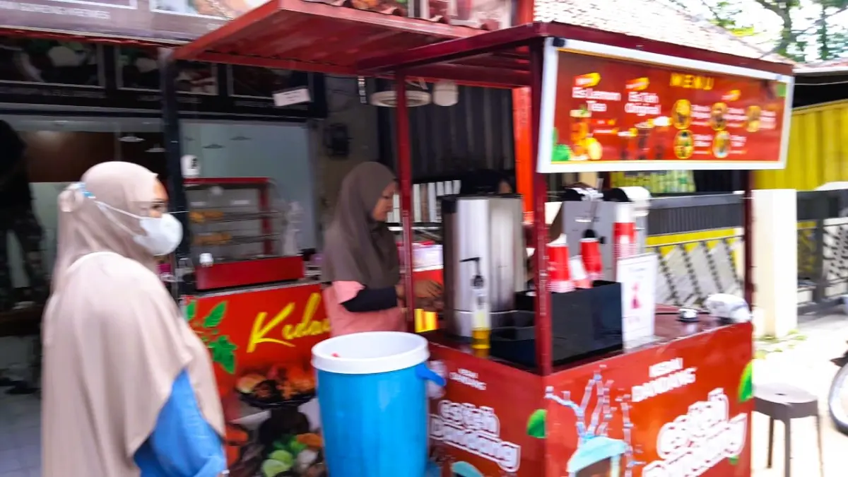 MENCARI REZEKI: Dua orang pekerja di Jalan Kabupaten Pamekasan sedang melayani pembeli, Selasa (28/4).