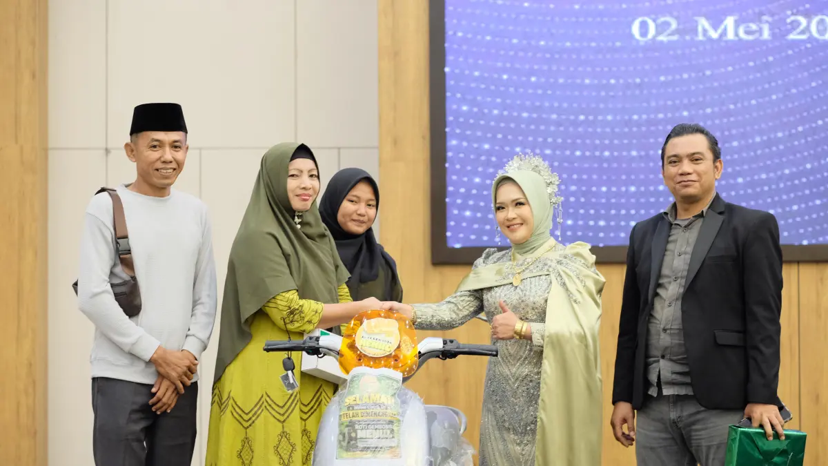 TAK LUPA PELANGGAN: Owner Roti Menul Indonesia Fawaid Sulaiman dan Ramadani (kanan) menyerahkan hadiah sepeda listrik kepada pelanggan yang beruntung dalam undian kupon Herlina Efendi pada malam Spectacular Menul Award 2026 dan Intimate Dinner di Ballroom Hotel Myze pada Sabtu (2/5) malam. 