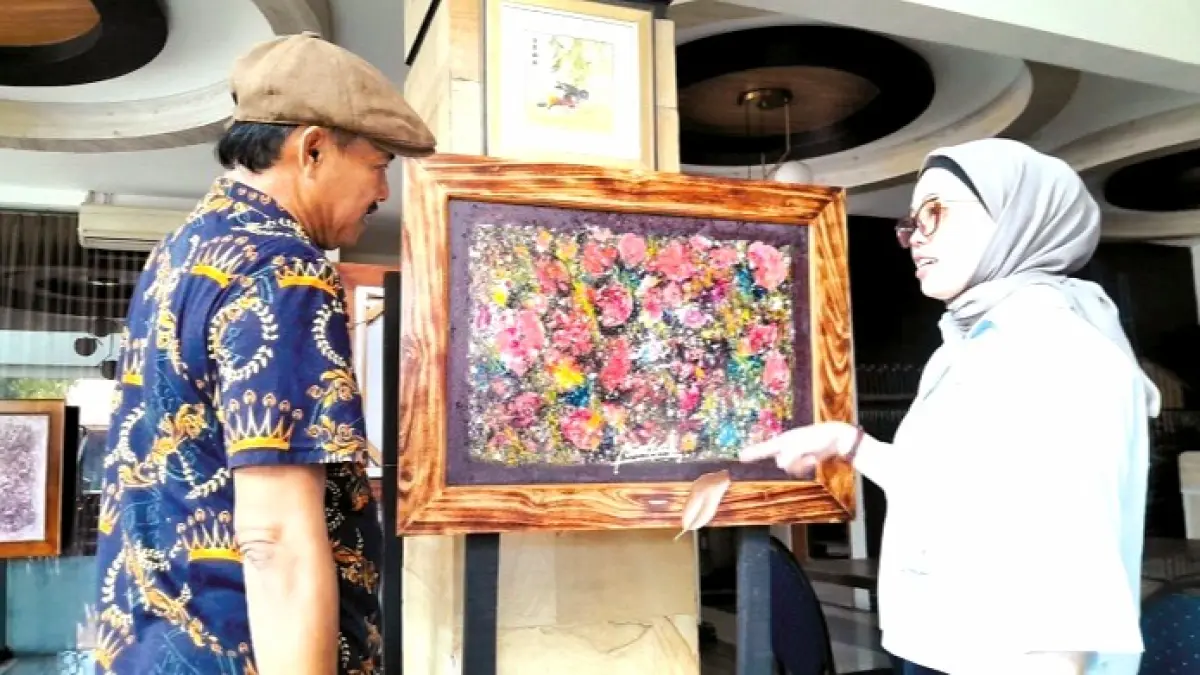 PENUH MAKNA: Pak Guru Budi sedang menjelaskan tentang lukisannya kepada pengunjung Kamis (7/5). (M. KHOLIL RAMLI/JPRM)