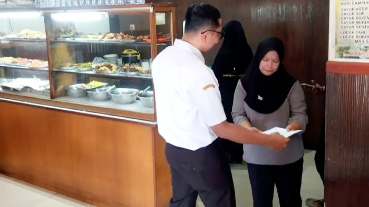 TIDAK TAAT: Petugas saat menyerahkan surat edaran kepada pekerja Rumah Makan Pecel Madiun Selasa (5/5). (PEMKAB UNTUK JPRM)