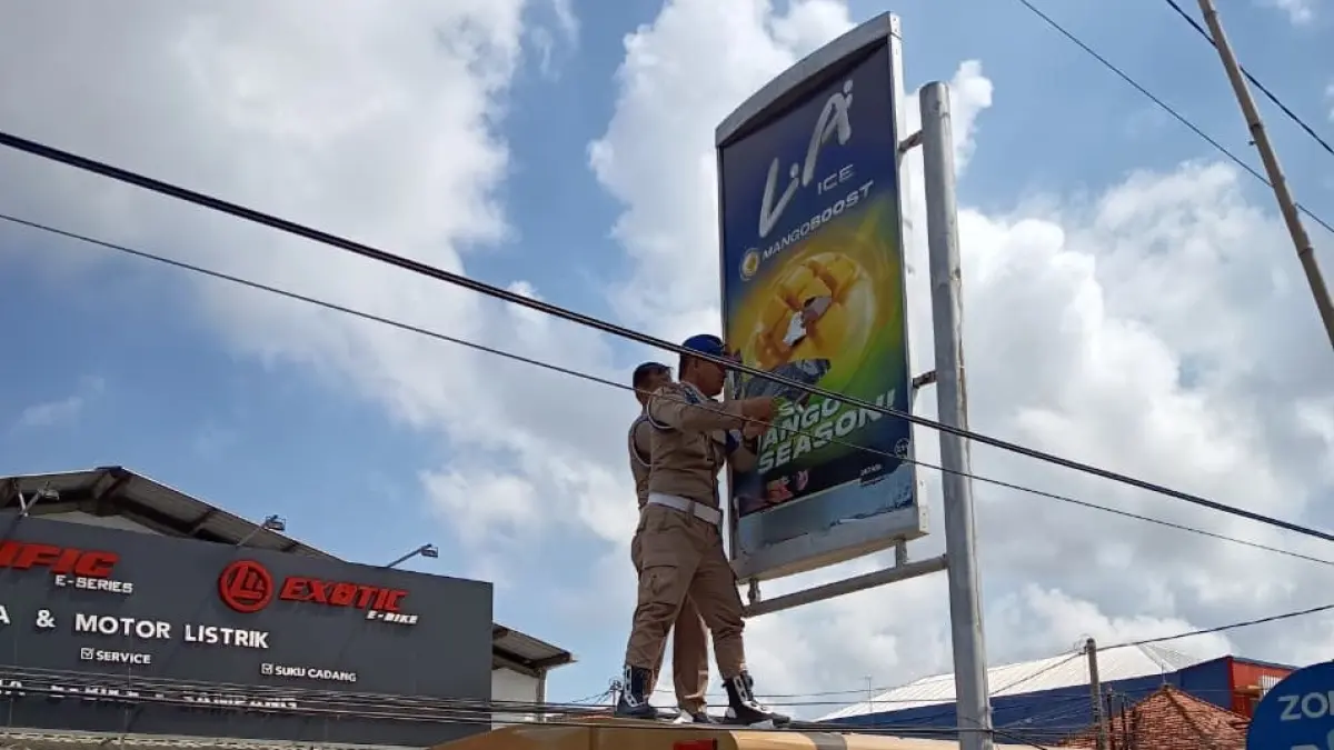 DITERTIBKAN: Petugas Satpol PP Sampang mencopot banner yang melanggar di Jalan Merapi, Sampang, Selasa (19/5).