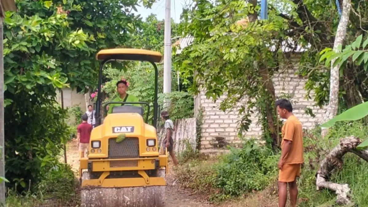 GOTONG ROYONG: Alat berat bantuan dari Poltera sedang mengerjakan perbaikan jalan Dusun Rabejateh, Desa Taddan, Kecamatan Camplong, Sampang, pada Sabtu (23/5).