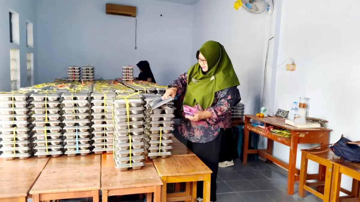 LANCAR: Guru SMPN 2 Bangkalan mengecek menu MBG sebelum dibagikan kepada siswa, Kamis (9/4). (SATGAS MBG UNTUK JPRM)