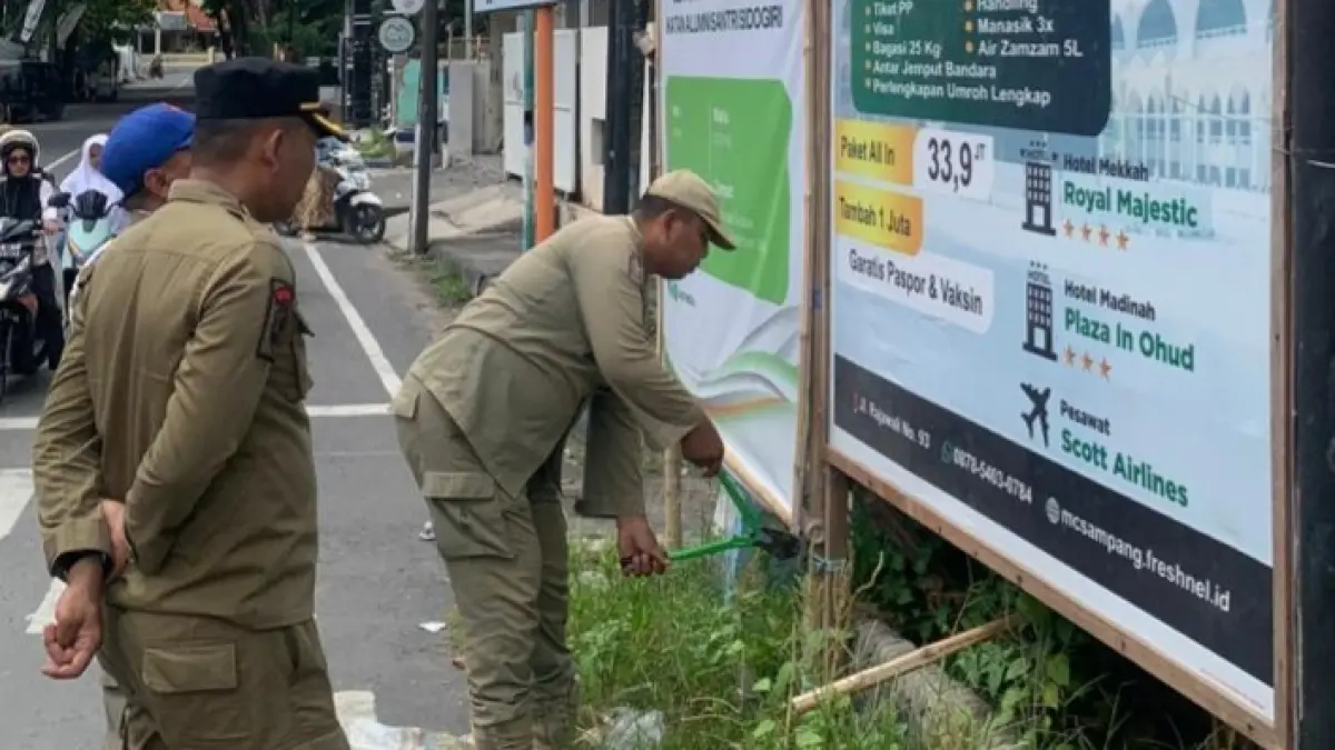 TIDAK TAAT: Satpol PP Sampang menertibkan banner yang melanggar di Jalan Merapi, Sampang, beberapa waktu lalu. (SATPOL PP UNTUK JPRM)