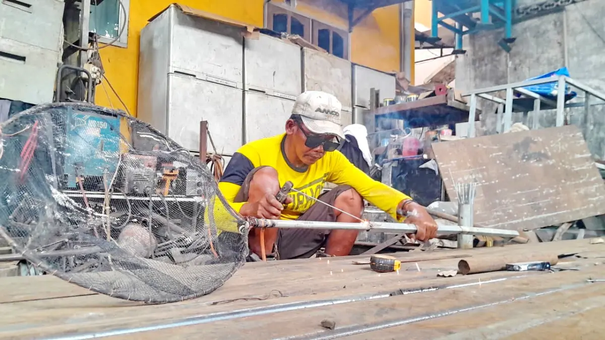 ASAH SKILL: Seorang pekerja las di Jalan Amin Jakfar, Kelurahan Gladak Anyar, Kecamatan Kota Pamekasan, sedang menyelesaikan pekerjaannya.