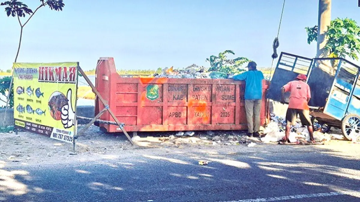 BEKERJA: Petugas kebersihan mengangkut sampah dari gerobak ke kontainer di Jalan Raya Lenteng–Batuan, Pabian, Sumenep, Minggu (31/5). (MOH. LATIF/JPRM)