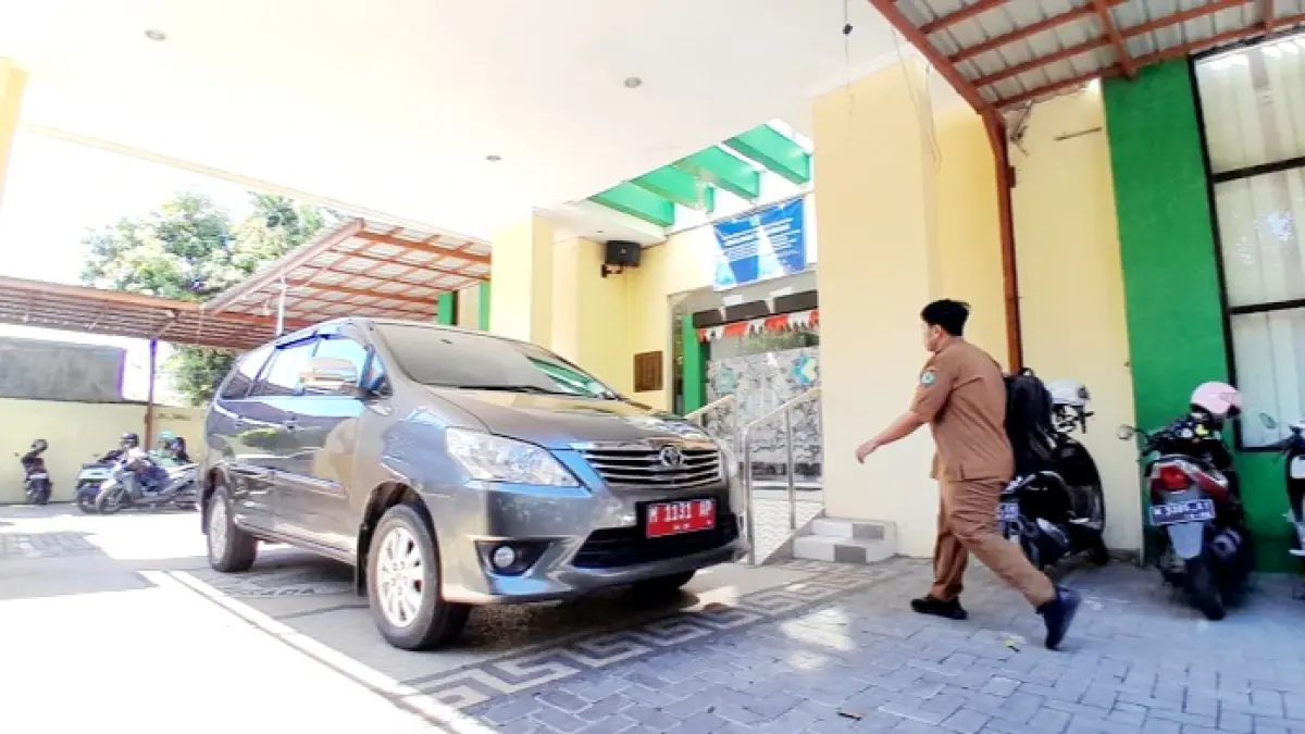 LENGANG: Seorang pegawai berjalan di dekat kendaraan dinas yang terparkir di depan kantor Dinkes Pamekasan Senin (8/6). (M. KHOLIL RAMLI/JPRM)
