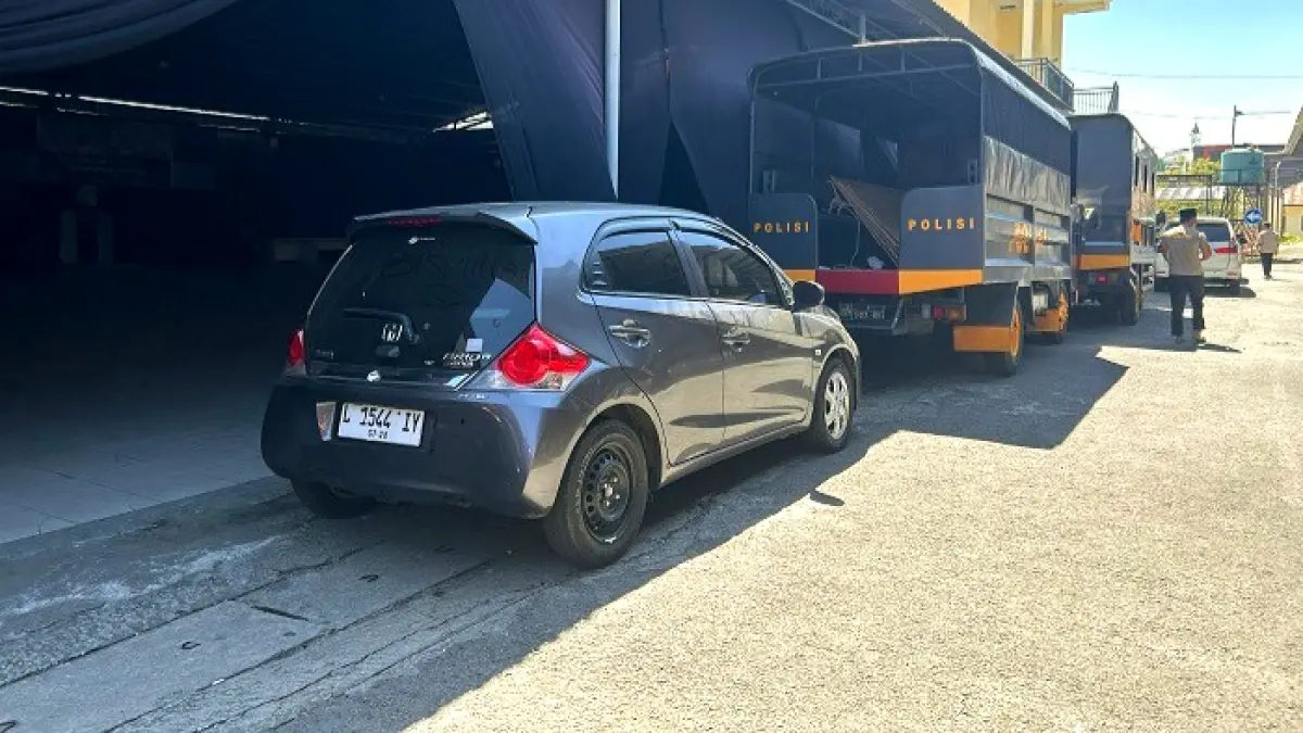 DIAMANKAN: Polisi berada di sekitar mobil Honda Brio nopol L 1544 IY di halaman Polres Sampang Kamis (11/6). (UBAIDILLAHIR RA’IE/JPRM)