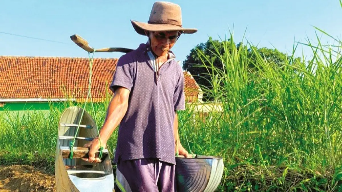 PENUH HARAP: Lasip, petani asal Desa Waru Barat, Kecamatan Waru, Pamekasan, menyiram tembakau di ladangnya, Rabu (20/5). (MOH. IQBAL AFGANI/JPRM)