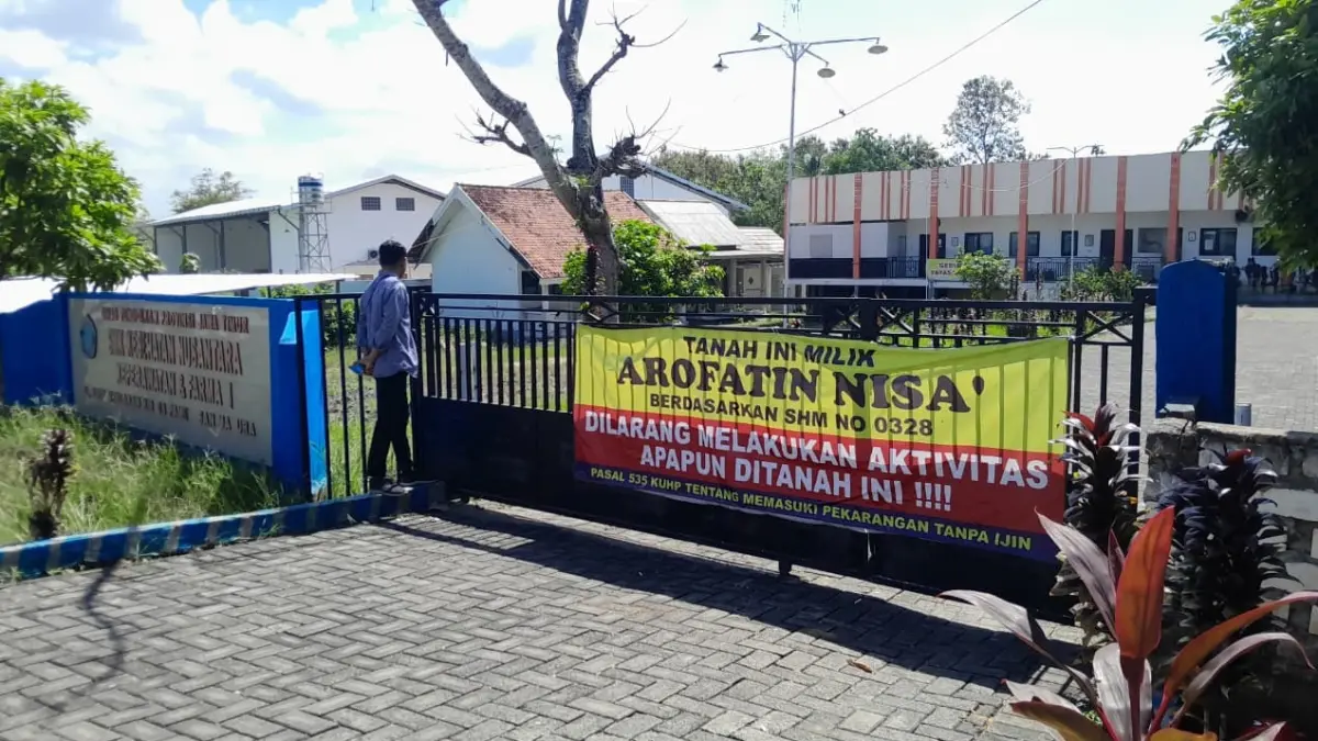 AKSES DITUTUP: Seorang warga sedang berada di lingkungan SMK Kesehatan Nusantara, Pamekasan, yang dalam kondisi disegel.