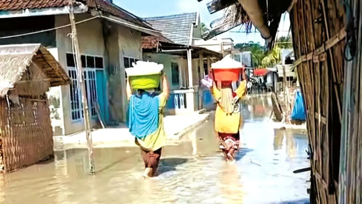 BANJIR ROB: Warga melewati jalan yang terendam di Desa Sadulang, Kecamatan Sapeken, Sumenep. (ERLINA FATIN UNTUK JPRM)