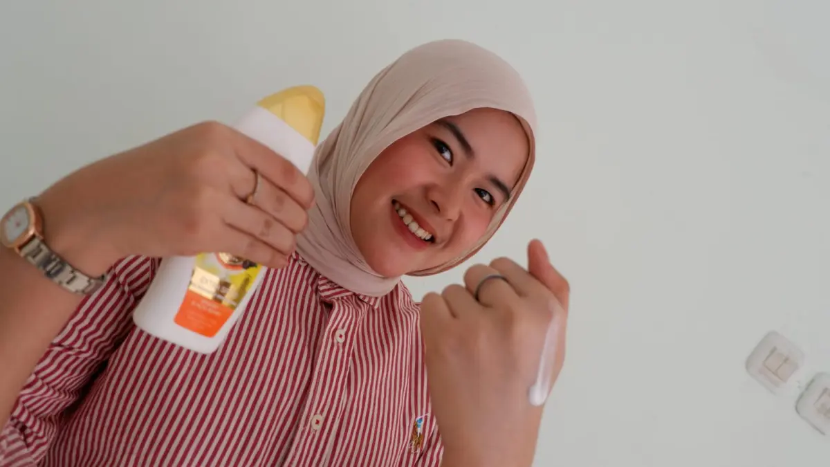 PRAKTIS: Zuhroni mengoleskan body lotion ke bagian tangannya.