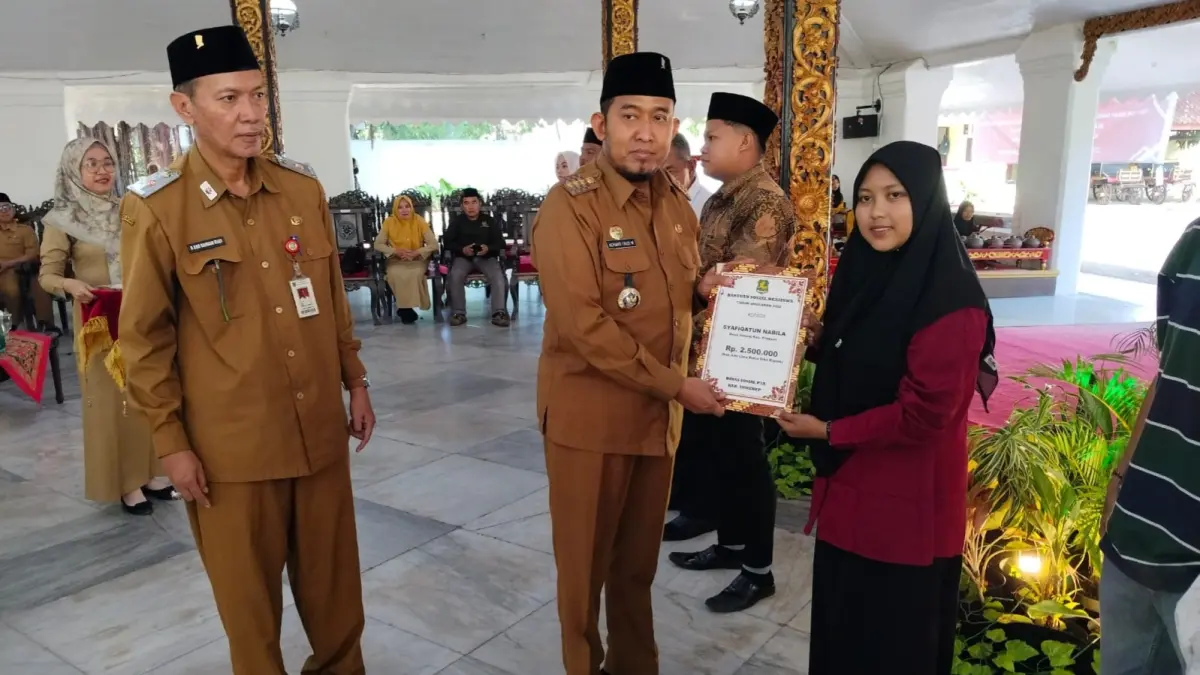 MELAYANI: Kepala Dinsos P3A Sumenep Abd. Rahman Riadi bersama Bupati Achmad Fauzi Wongsojudo menyalurkan bantuan beasiswa di Pendopo Agung Keraton Sumenep, Senin (24/6).