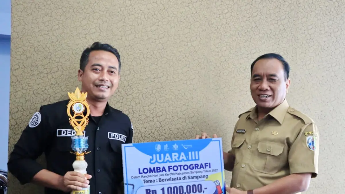 JUARA: Aipda Dedy Sukadarisman menerima penghargaan lomba fotografi dari Kadisporabudpar Sampang Marnilem dalam rangka peringatan HUT  Kabupaten Sampang 2022.